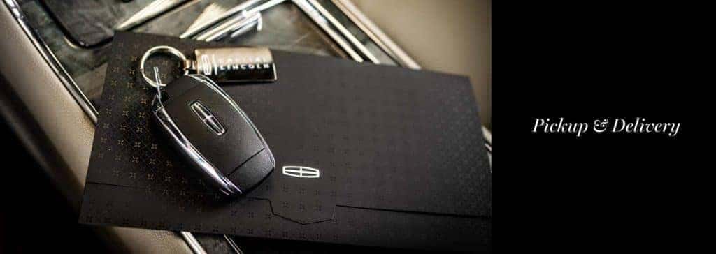 Car key and envelope on a console with "Pickup & Delivery" text, highlighting a service feature.