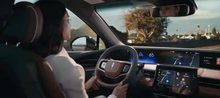 Driver in modern car interacts with digital dashboard displaying navigation and speed.