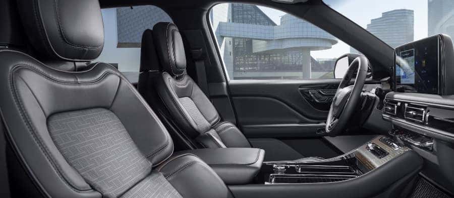 Luxurious car interior with leather seats, modern dashboard, and touchscreen display against a city backdrop.