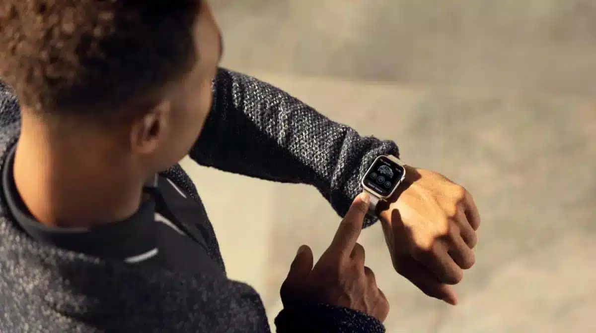 Person interacting with a smartwatch, displaying app icons on the screen.