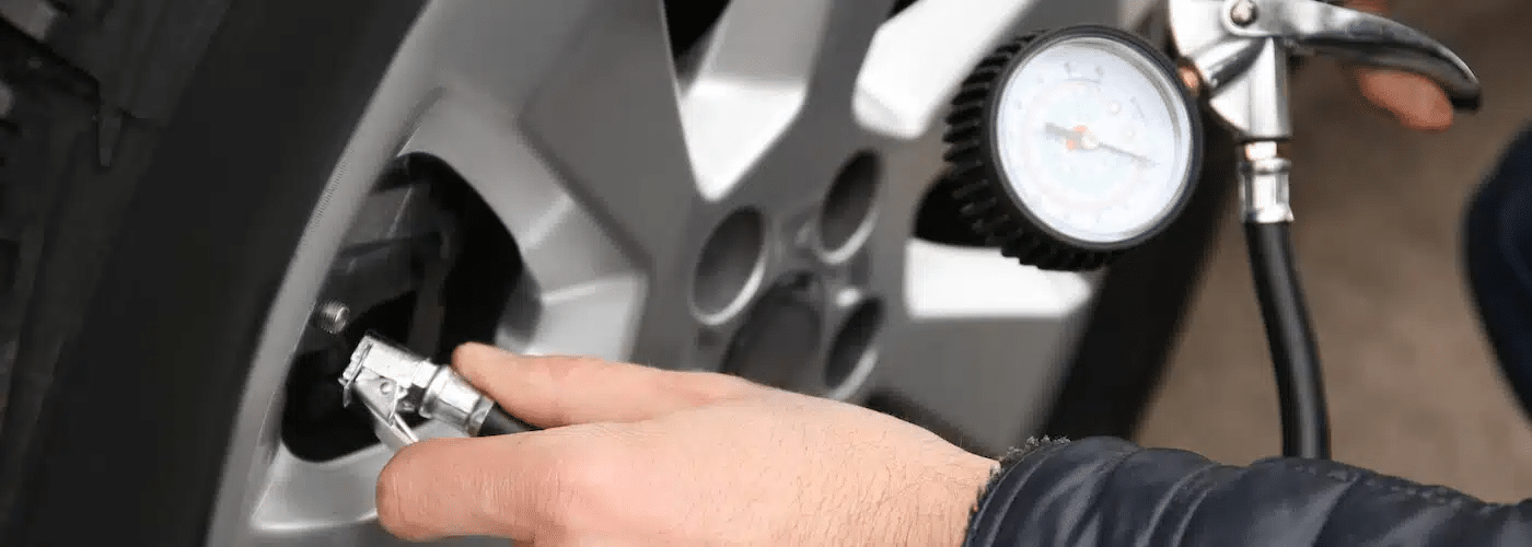 Person checking car tire pressure with a gauge, ensuring proper inflation.