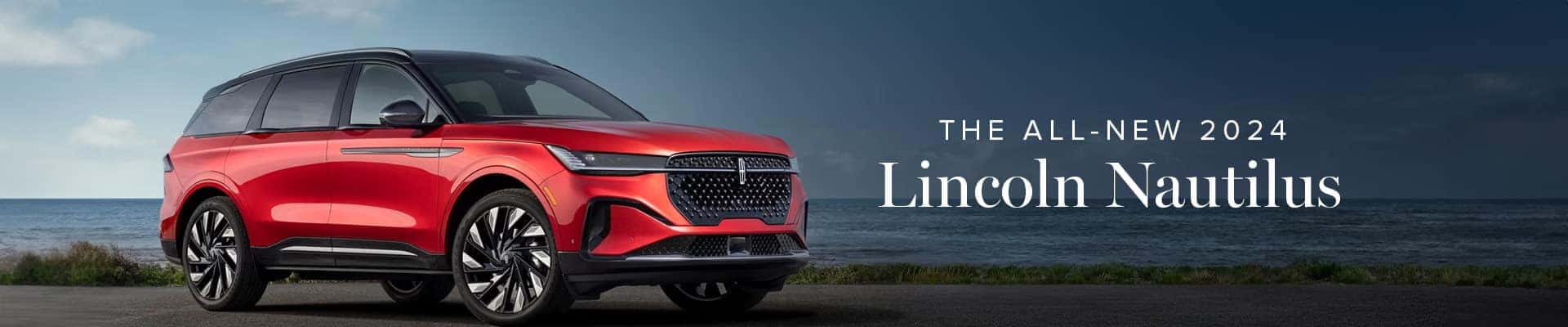 Red 2024 Lincoln Nautilus SUV parked on a coastal road, with ocean in the background.