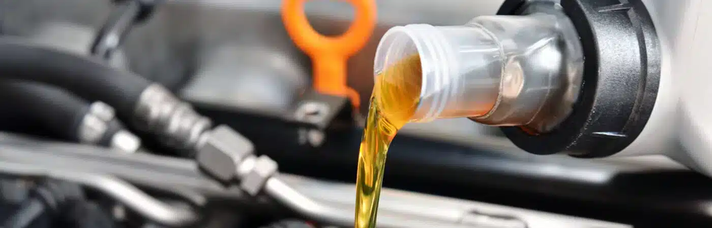 Pouring engine oil into a vehicle's engine with visible dipstick in the background.
