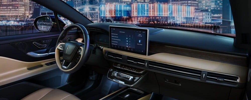 Luxury car interior featuring a sleek dashboard, large touchscreen, and premium leather seats with a cityscape view.