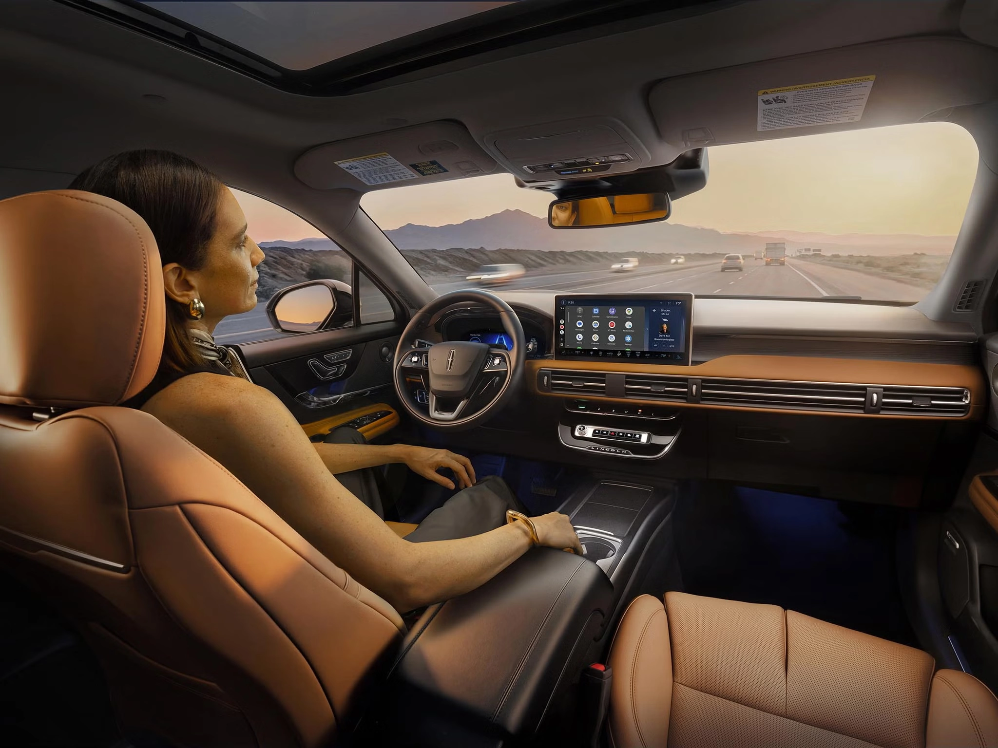 Man relaxing in a self-driving car, hands-free, with a digital dashboard displaying information.